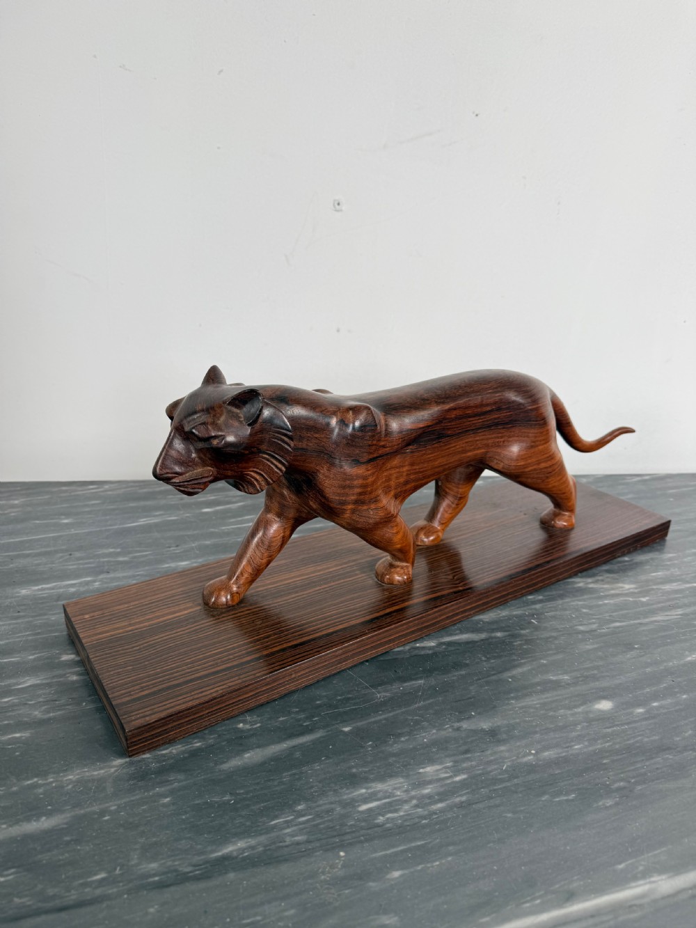 A carved dark wood Art Deco sculpture depicting a prowling panther mounted on a matching rectangular timber base. View X