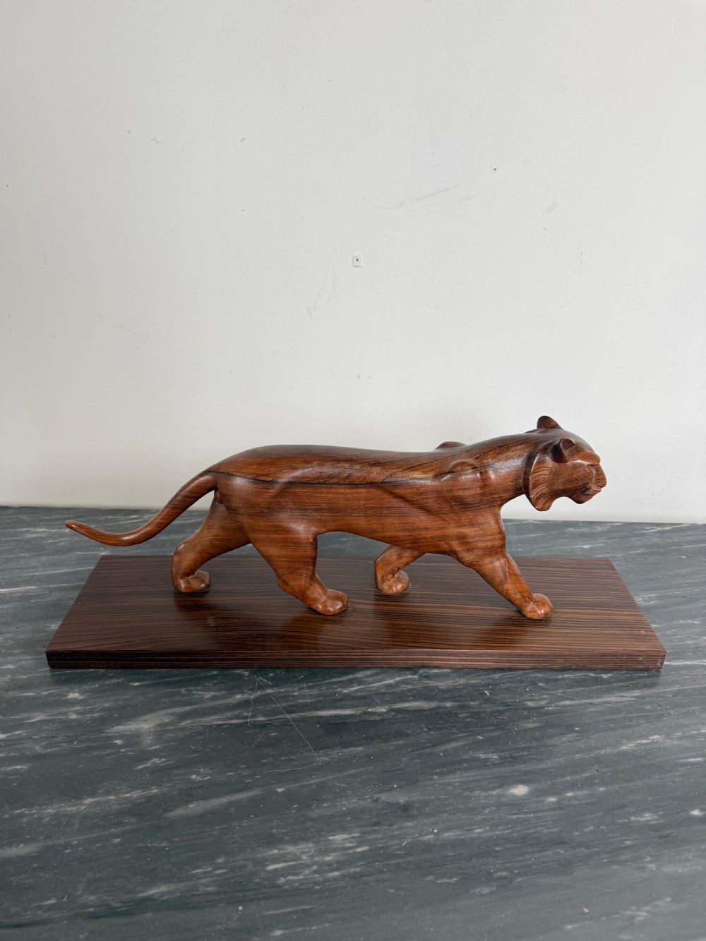 A carved dark wood Art Deco sculpture depicting a prowling panther mounted on a matching rectangular timber base. View XI