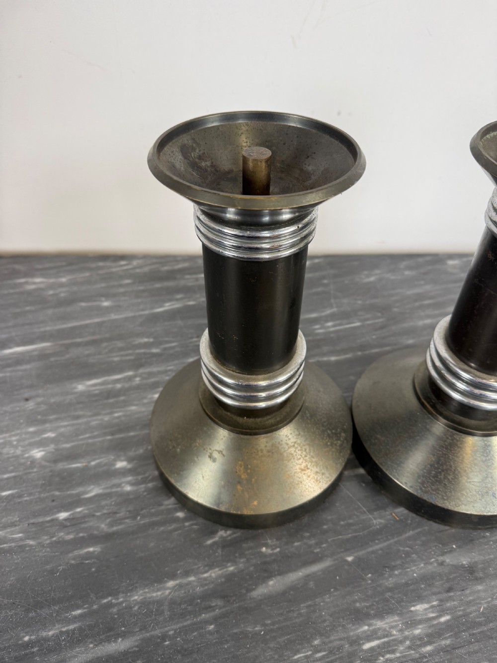 A pair of dark patinated metal Art Deco candlesticks featuring cylindrical columns, flared conical bases, and polished chrome ribbed bands. View III