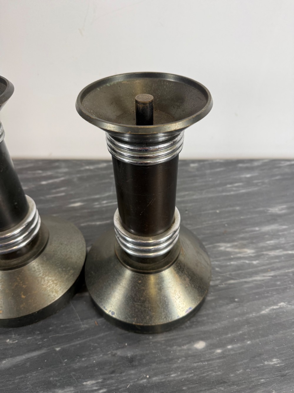 A pair of dark patinated metal Art Deco candlesticks featuring cylindrical columns, flared conical bases, and polished chrome ribbed bands. View IV