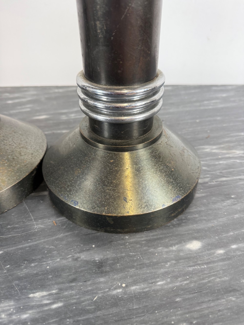 A pair of dark patinated metal Art Deco candlesticks featuring cylindrical columns, flared conical bases, and polished chrome ribbed bands. View V