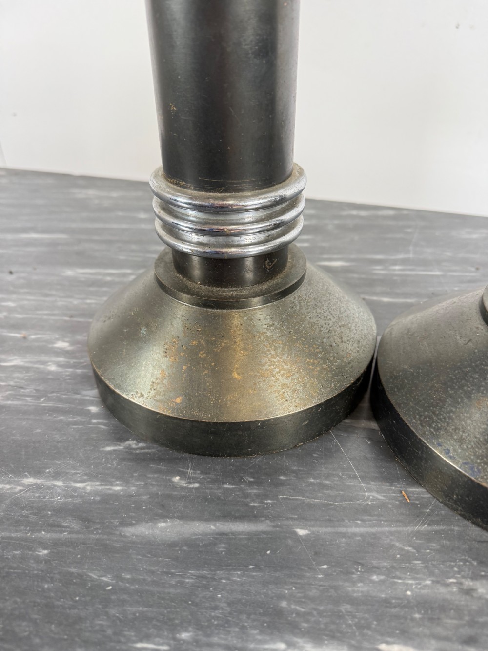A pair of dark patinated metal Art Deco candlesticks featuring cylindrical columns, flared conical bases, and polished chrome ribbed bands. View VI