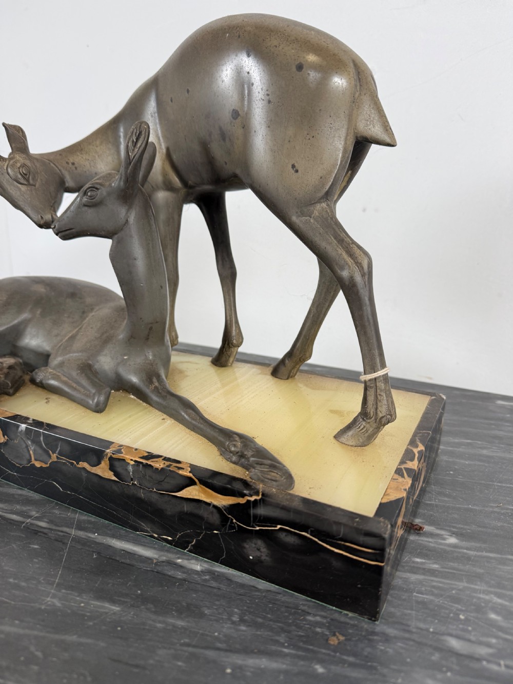 An Art Deco spelter sculpture featuring one standing horned deer and one reclining deer mounted on a rectangular black marble and amber onyx base. View IV