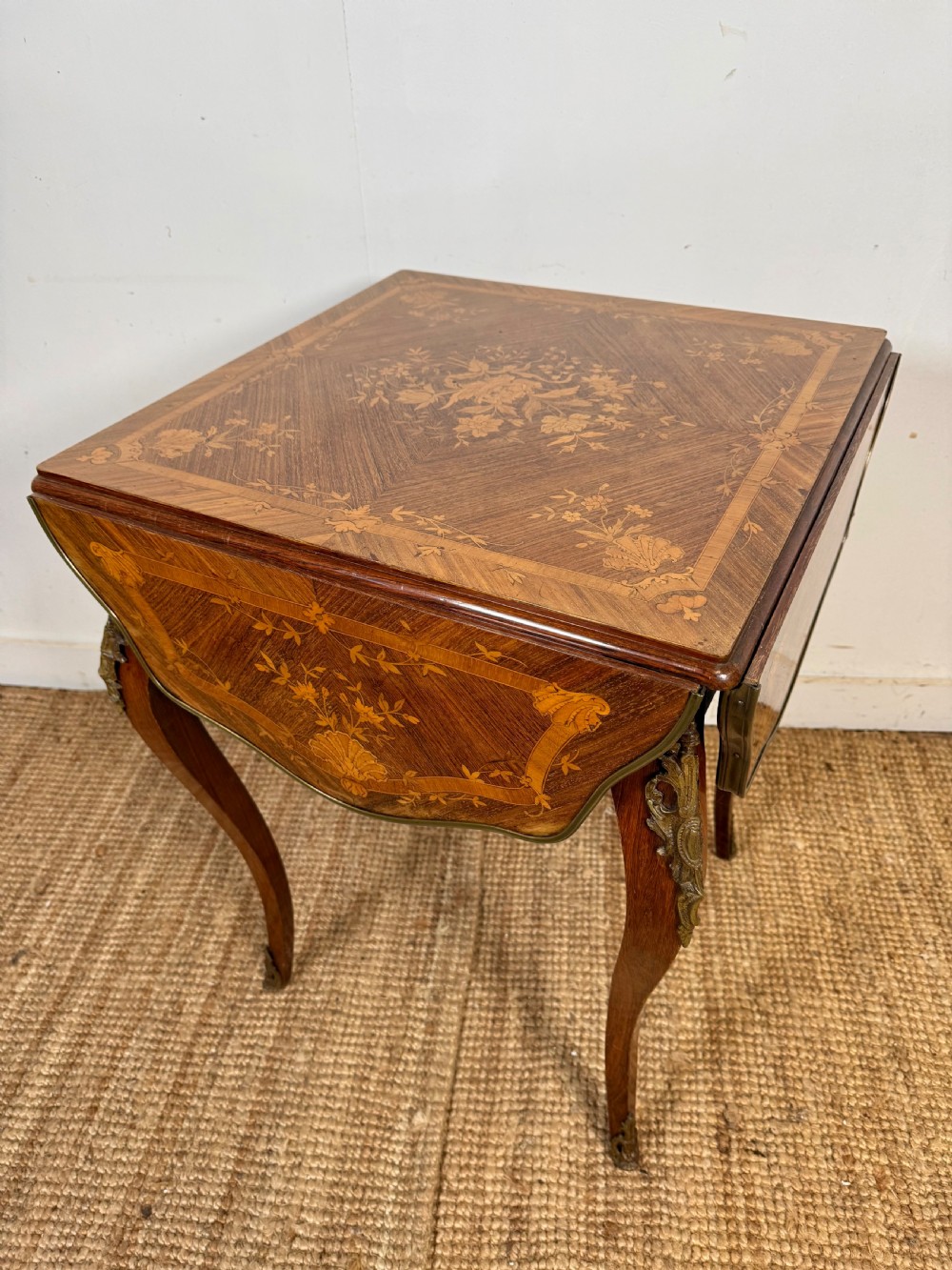 A French Napoleon III rosewood side table featuring floral marquetry inlays, drop leaves, and curved cabriole legs with brass mounts.