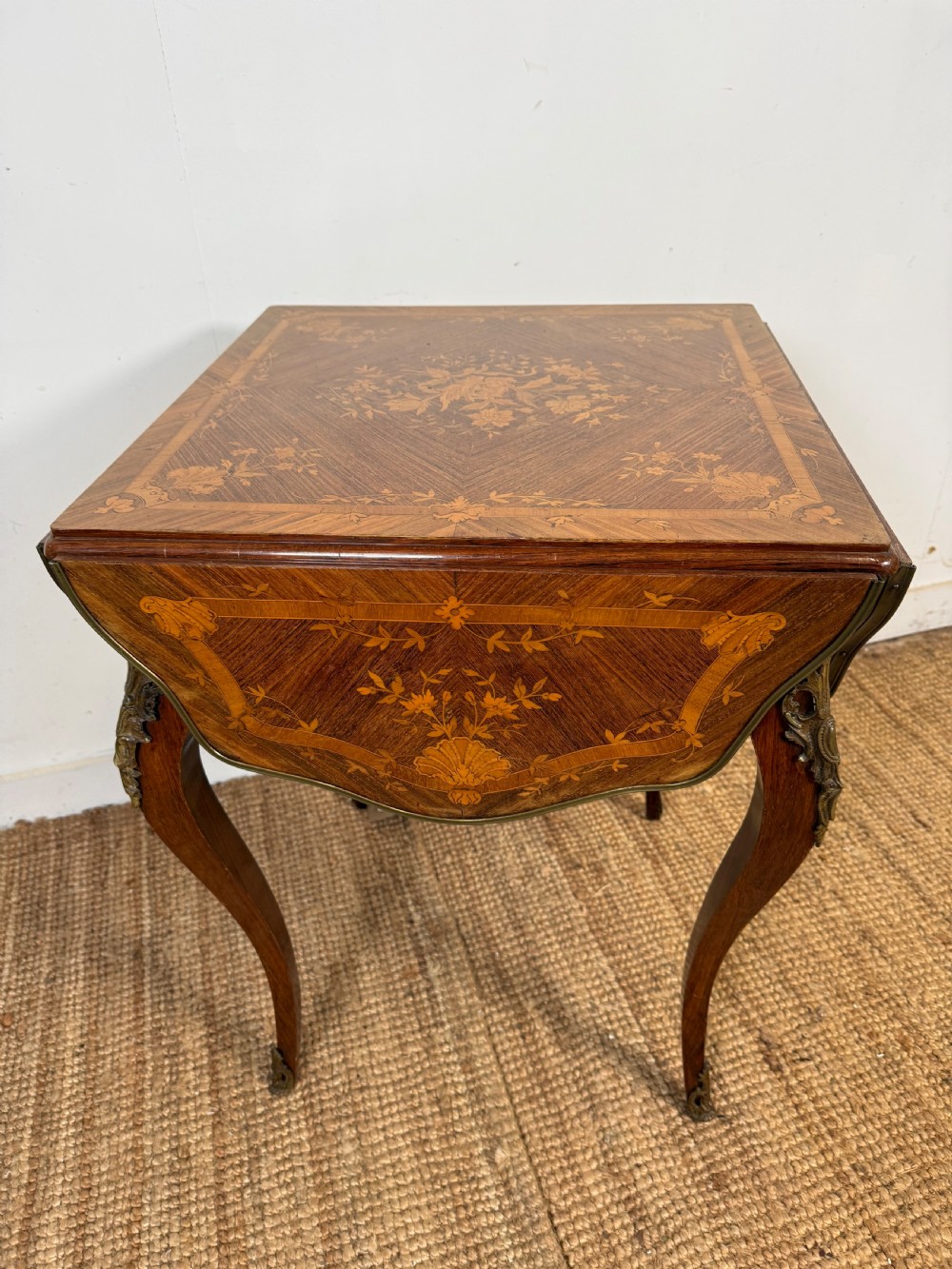 A French Napoleon III rosewood side table featuring floral marquetry inlays, drop leaves, and curved cabriole legs with brass mounts. View II