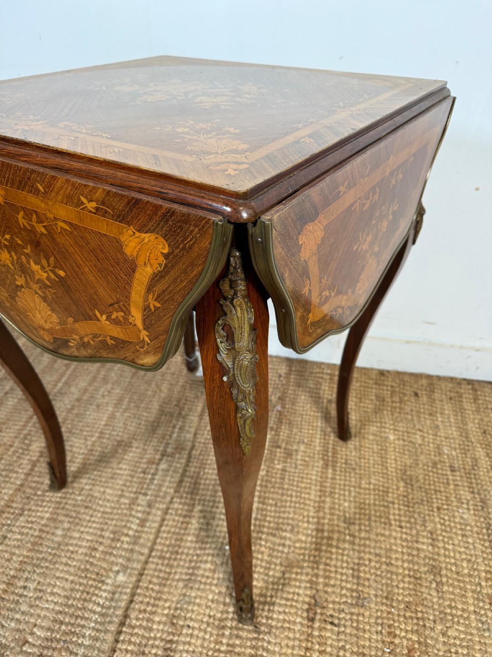 A French Napoleon III rosewood side table featuring floral marquetry inlays, drop leaves, and curved cabriole legs with brass mounts. View III