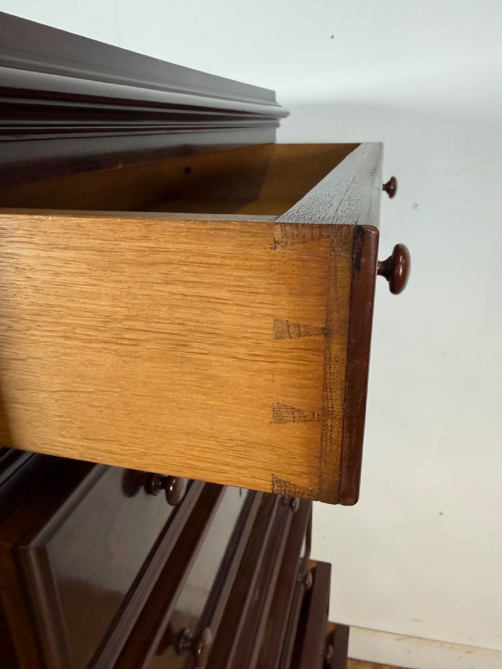 A tall, narrow flame mahogany semainier chest featuring seven drawers with turned knobs and central keyholes set on a moulded plinth base. View X