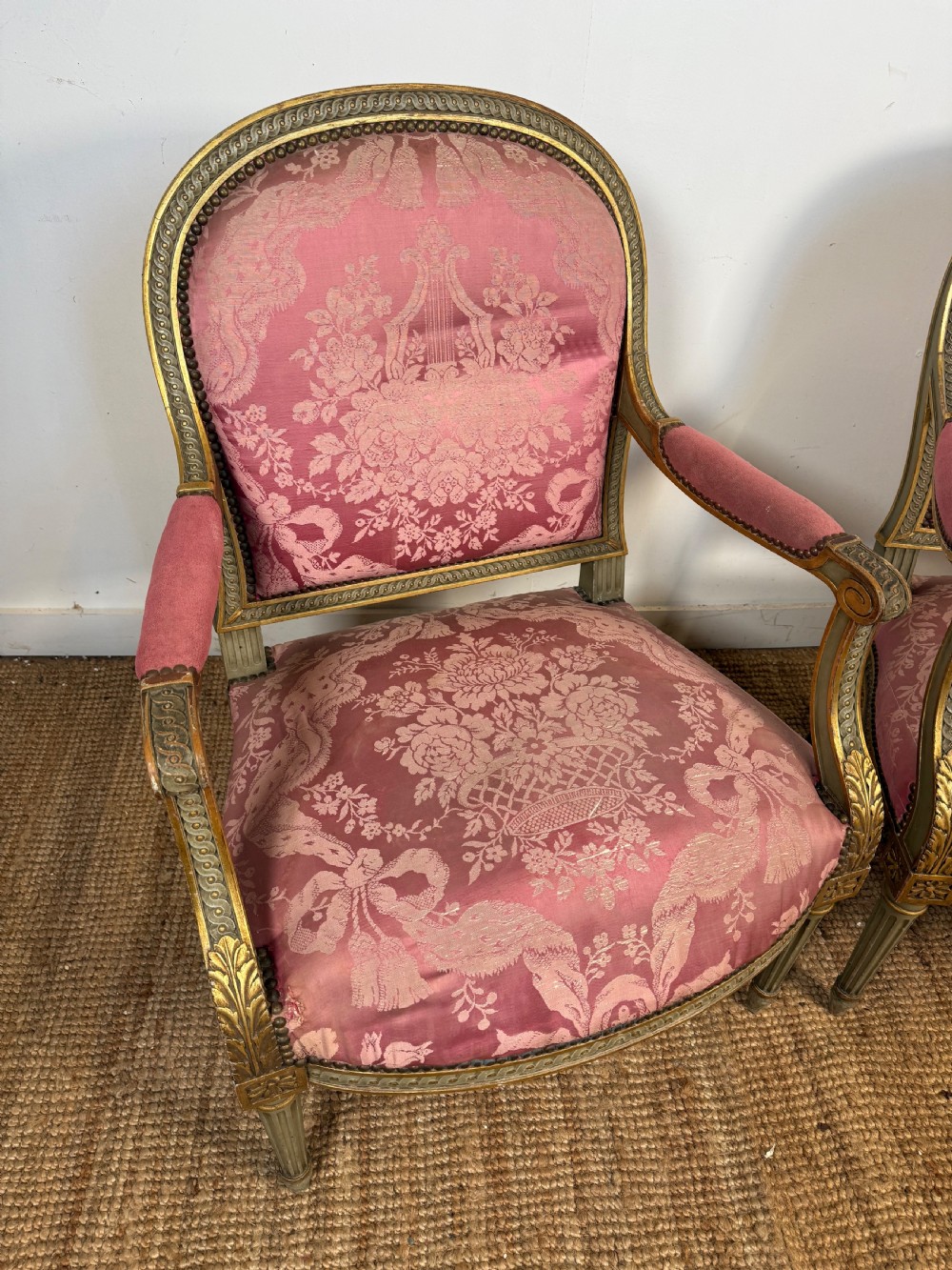A pair of Louis XVI style French open armchairs featuring carved giltwood frames, fluted legs, and pink damask pattern upholstery. View II