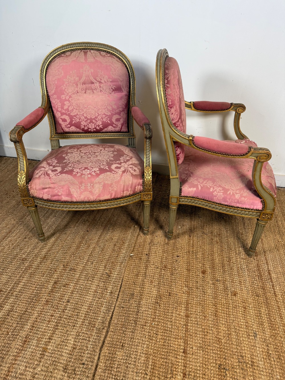 A pair of Louis XVI style French open armchairs featuring carved giltwood frames, fluted legs, and pink damask pattern upholstery. View V