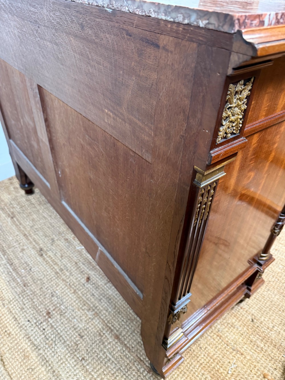 A 19th-century French mahogany commode featuring a red marble top, brass drop handles, and fluted corner columns. View XVIII