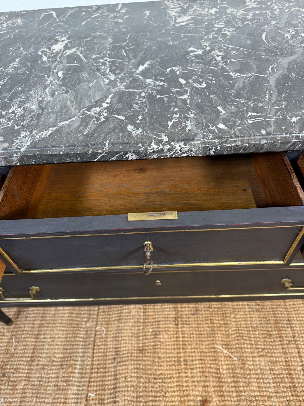 An early 19th-century black painted Louis XVI style commode featuring a grey marble top, brass trim, and fluted column legs. View XIII