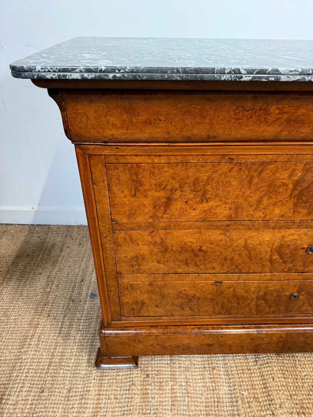 A rectangular 19th-century burr elm commode featuring a grey mottled marble top and three long drawers with central key escutcheons. View III