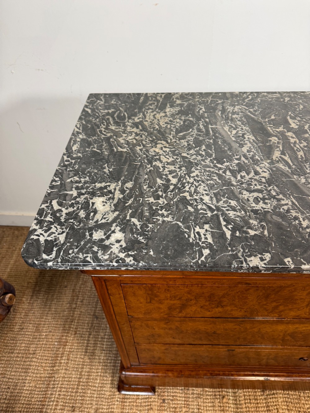 A rectangular 19th-century burr elm commode featuring a grey mottled marble top and three long drawers with central key escutcheons. View VI