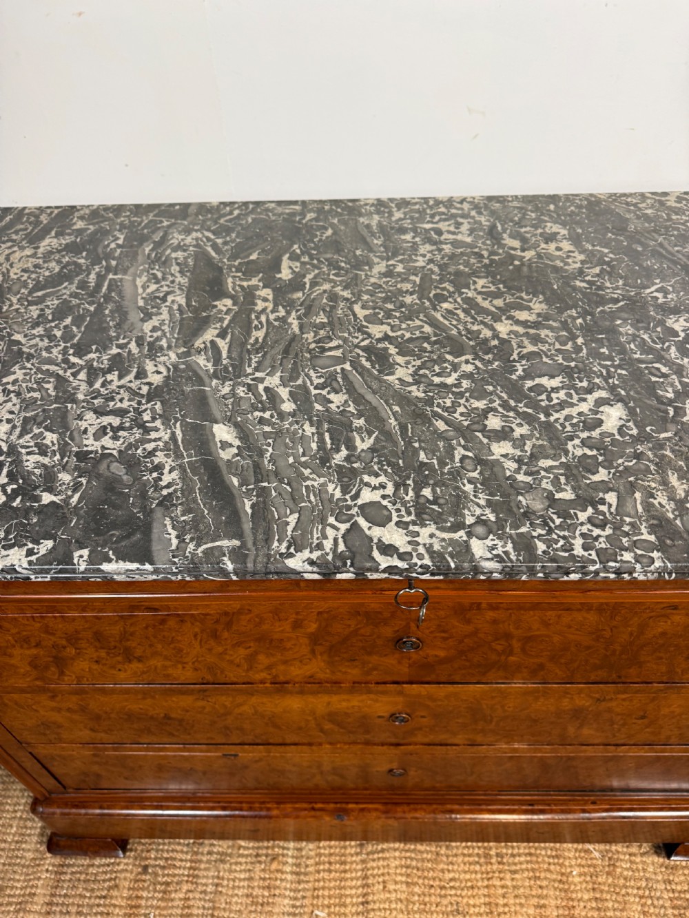 A rectangular 19th-century burr elm commode featuring a grey mottled marble top and three long drawers with central key escutcheons. View VII