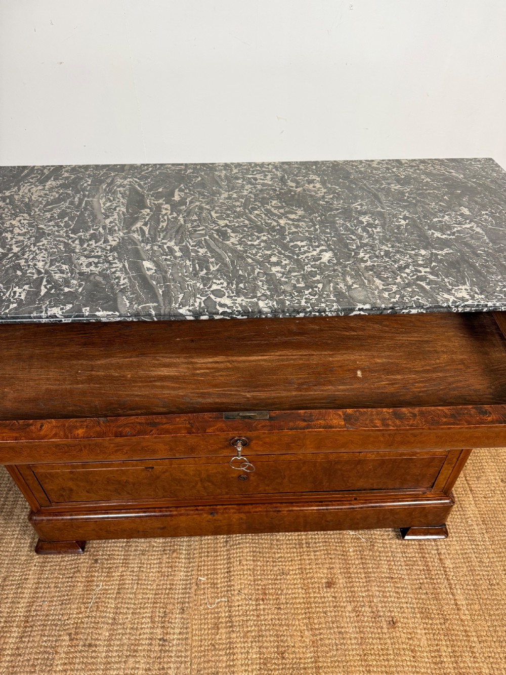 A rectangular 19th-century burr elm commode featuring a grey mottled marble top and three long drawers with central key escutcheons. View VIII