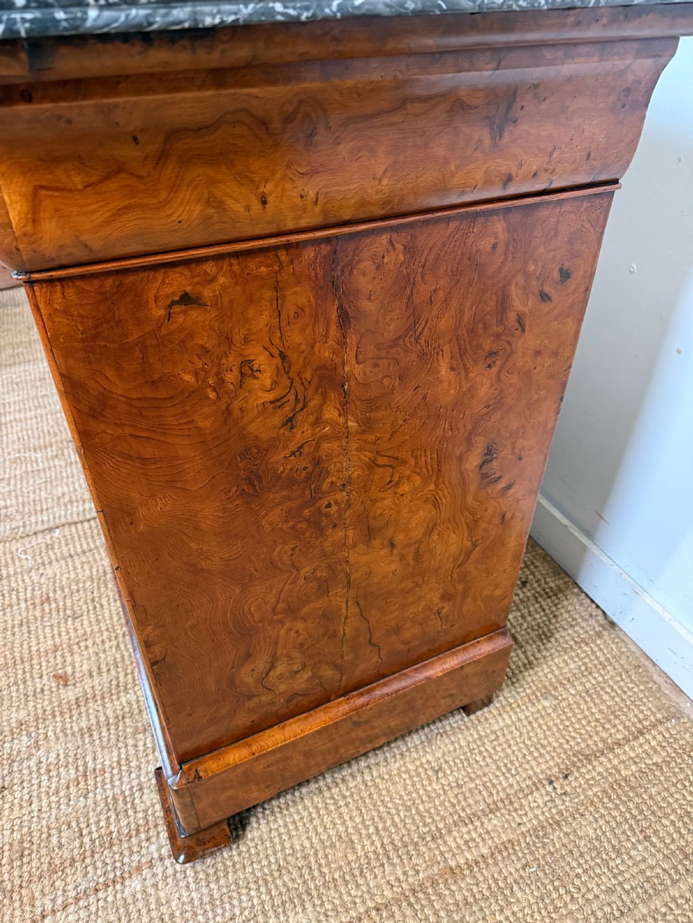 A rectangular 19th-century burr elm commode featuring a grey mottled marble top and three long drawers with central key escutcheons. View IX