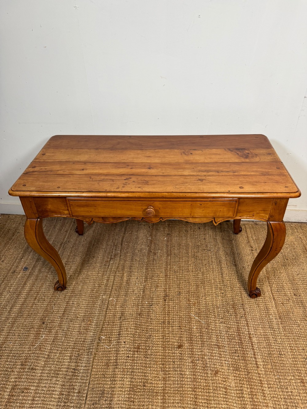 An early nineteenth-century French cherrywood side table featuring cabriole legs, a contoured apron with a single drawer, and a warm honey-coloured timber finish.