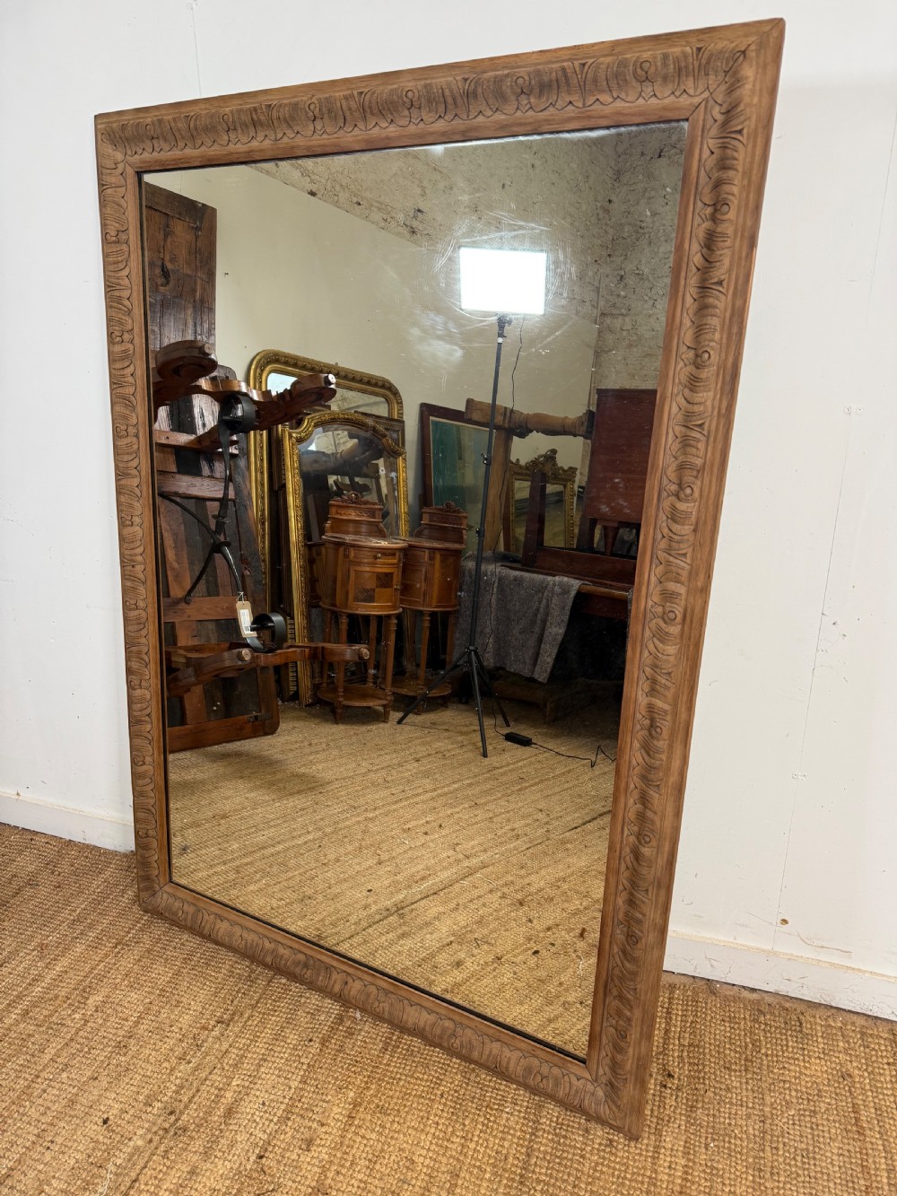 A large rectangular 19th-century wall mirror featuring a wide, hand-carved scrubbed oak frame with foliate border detailing.