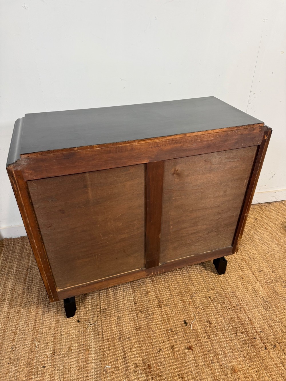 A French Art Deco ebonised black wooden commode featuring four stacked drawers with curved silver metal handles and a stepped top border. View XI