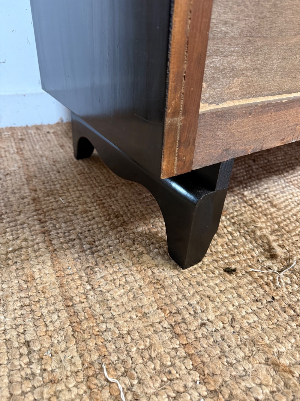 A French Art Deco ebonised black wooden commode featuring four stacked drawers with curved silver metal handles and a stepped top border. View XII
