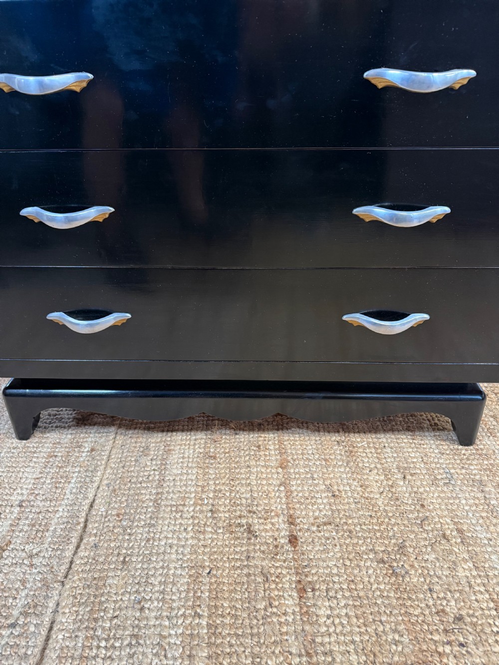 A French Art Deco ebonised black wooden commode featuring four stacked drawers with curved silver metal handles and a stepped top border. View XIII