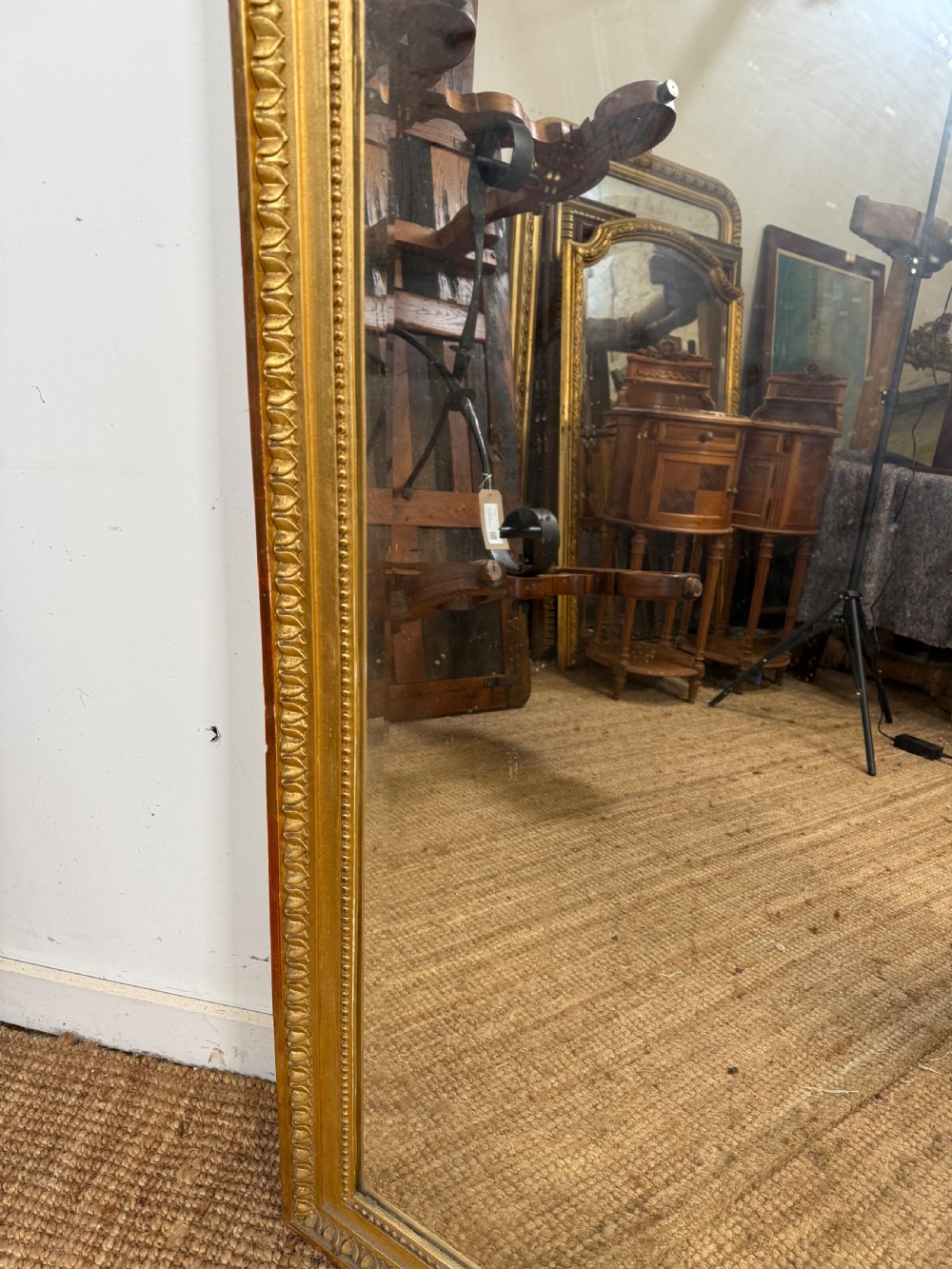 A rectangular antique wall mirror featuring a prominent ornate floral and ribbon carved crest in a gilded finish. View VIII