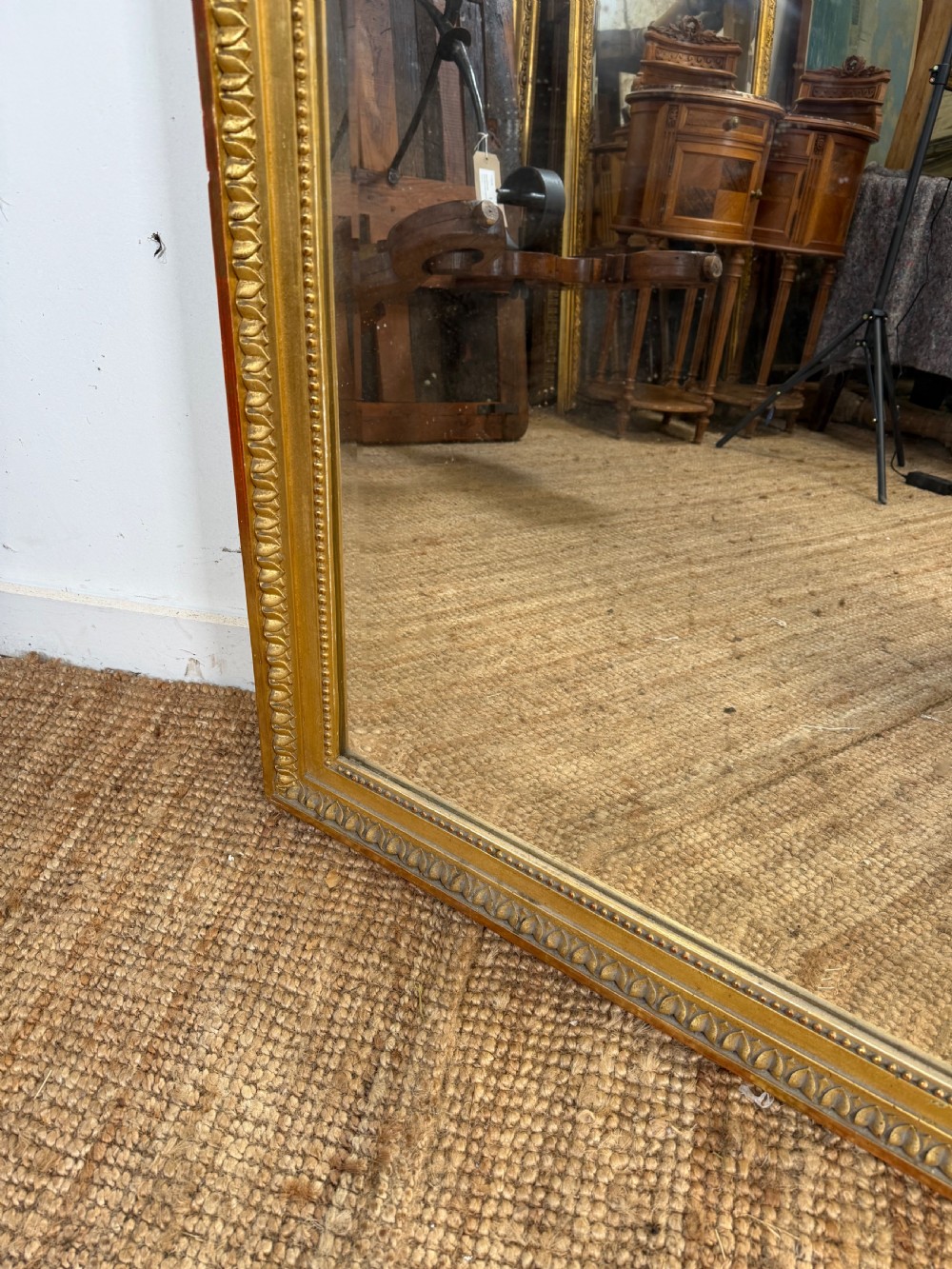 A rectangular antique wall mirror featuring a prominent ornate floral and ribbon carved crest in a gilded finish. View IX