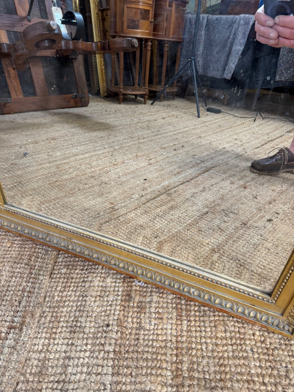 A rectangular antique wall mirror featuring a prominent ornate floral and ribbon carved crest in a gilded finish. View X
