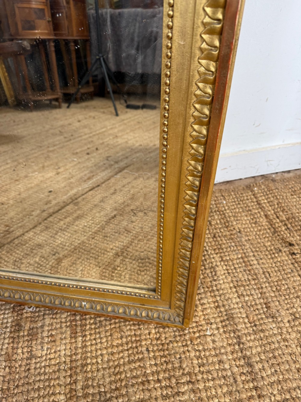 A rectangular antique wall mirror featuring a prominent ornate floral and ribbon carved crest in a gilded finish. View XI