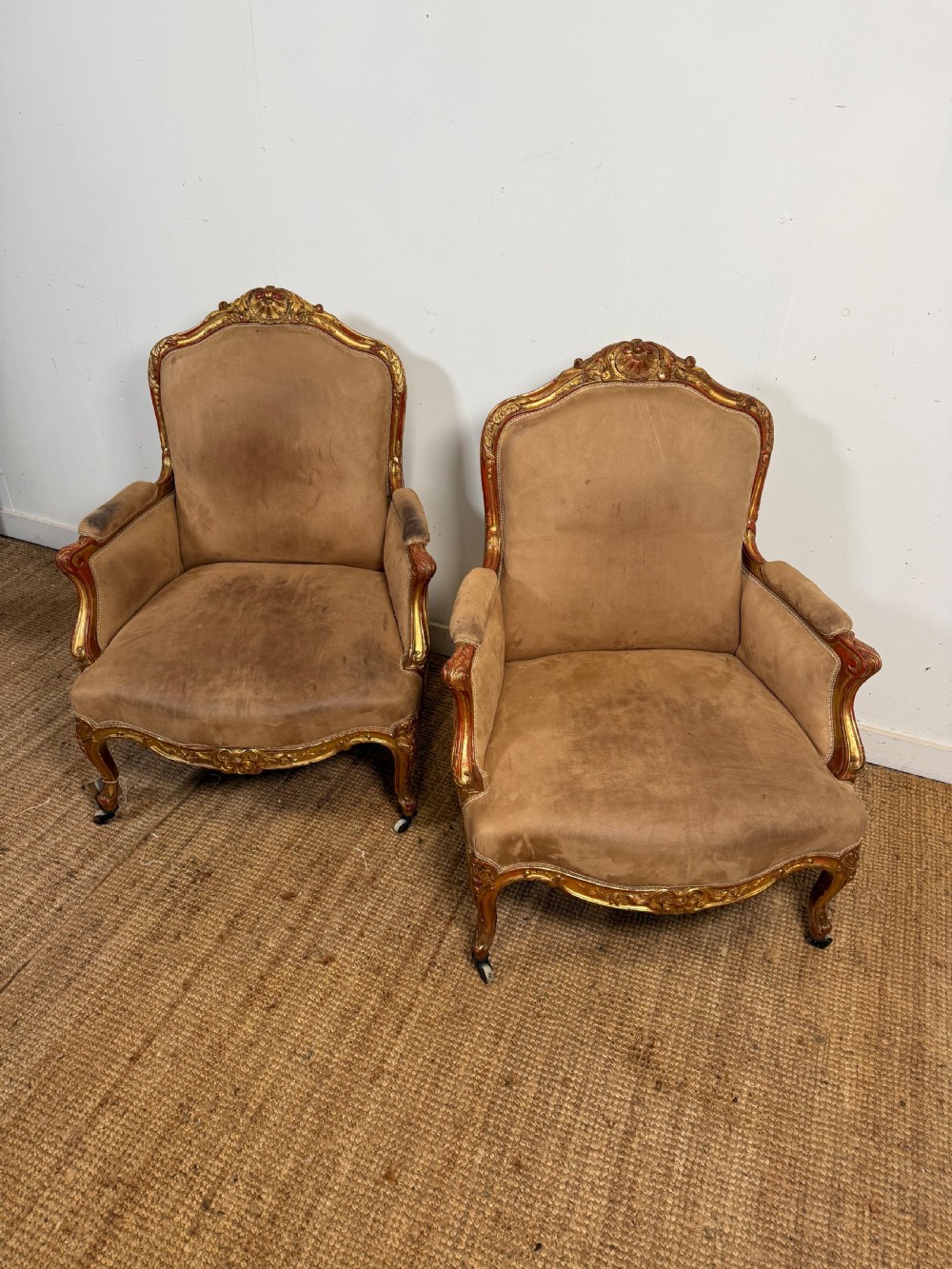 A pair of 19th-century French Napoleon III giltwood armchairs upholstered in taupe velvet with carved floral crests and cabriole legs.