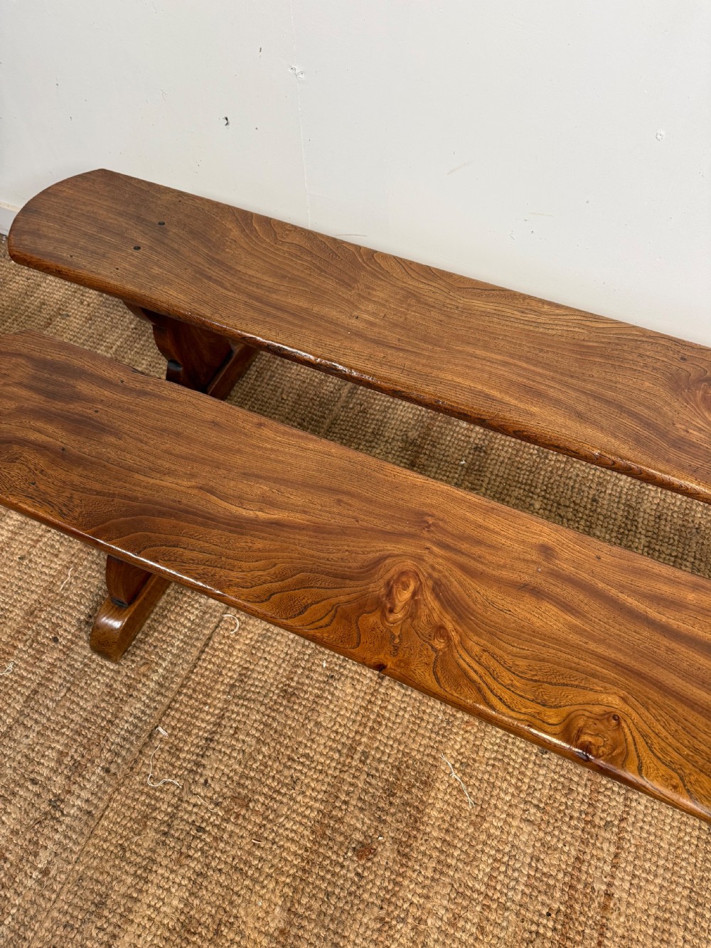 A pair of early 20th-century French rustic benches crafted from solid warm brown elm with visible wood grain and trestle end supports. View IV