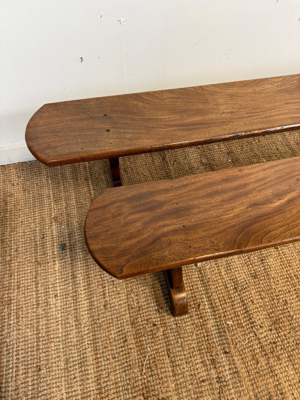 A pair of early 20th-century French rustic benches crafted from solid warm brown elm with visible wood grain and trestle end supports. View V