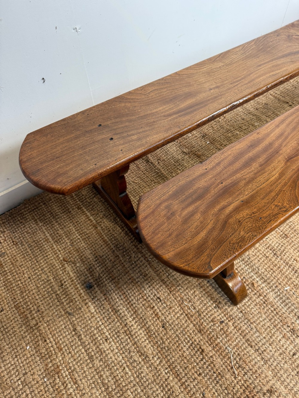 A pair of early 20th-century French rustic benches crafted from solid warm brown elm with visible wood grain and trestle end supports. View VI