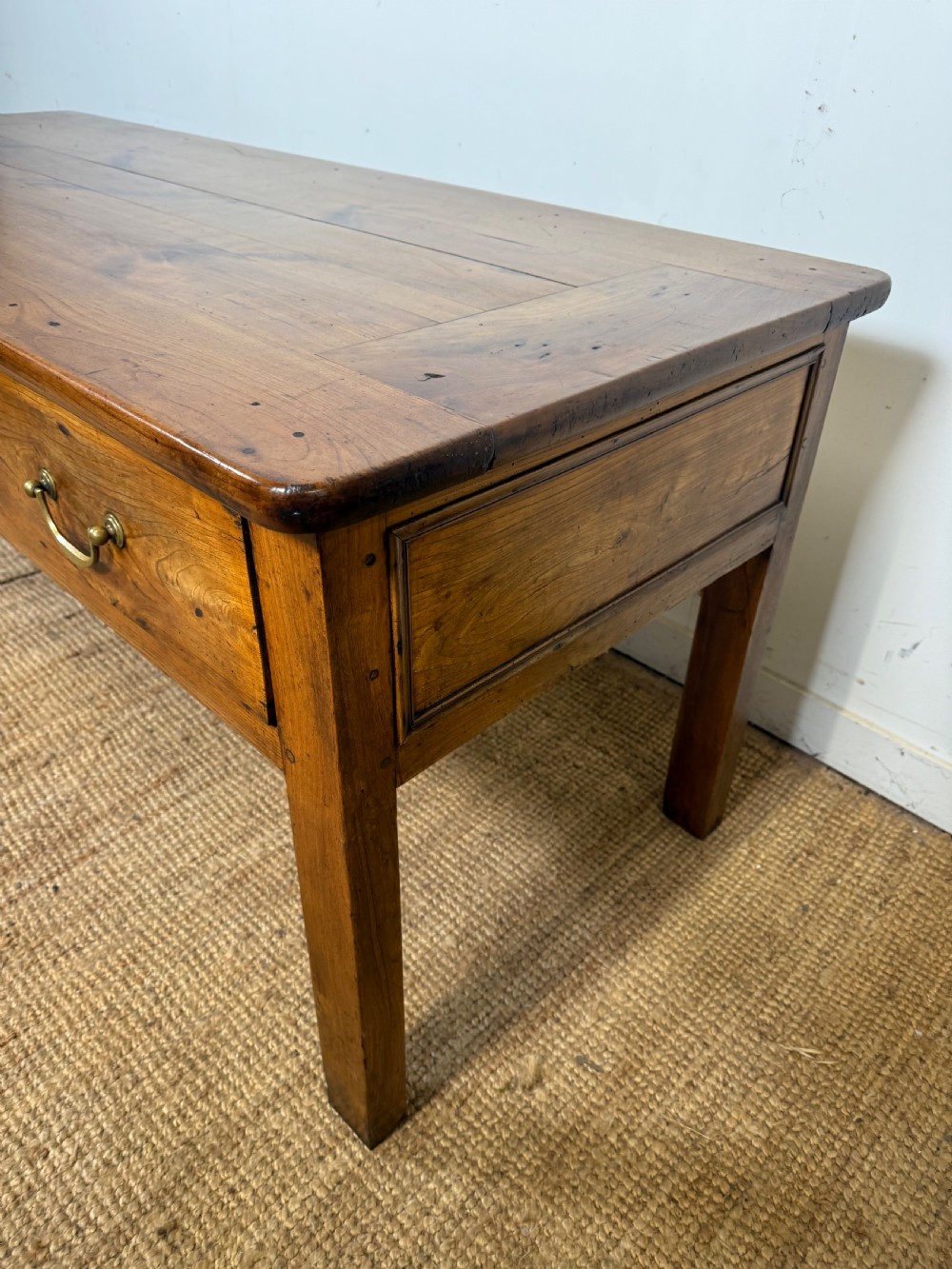 A 19th-century French provincial wooden dresser base featuring three drawers with brass bail handles set on straight legs. View II