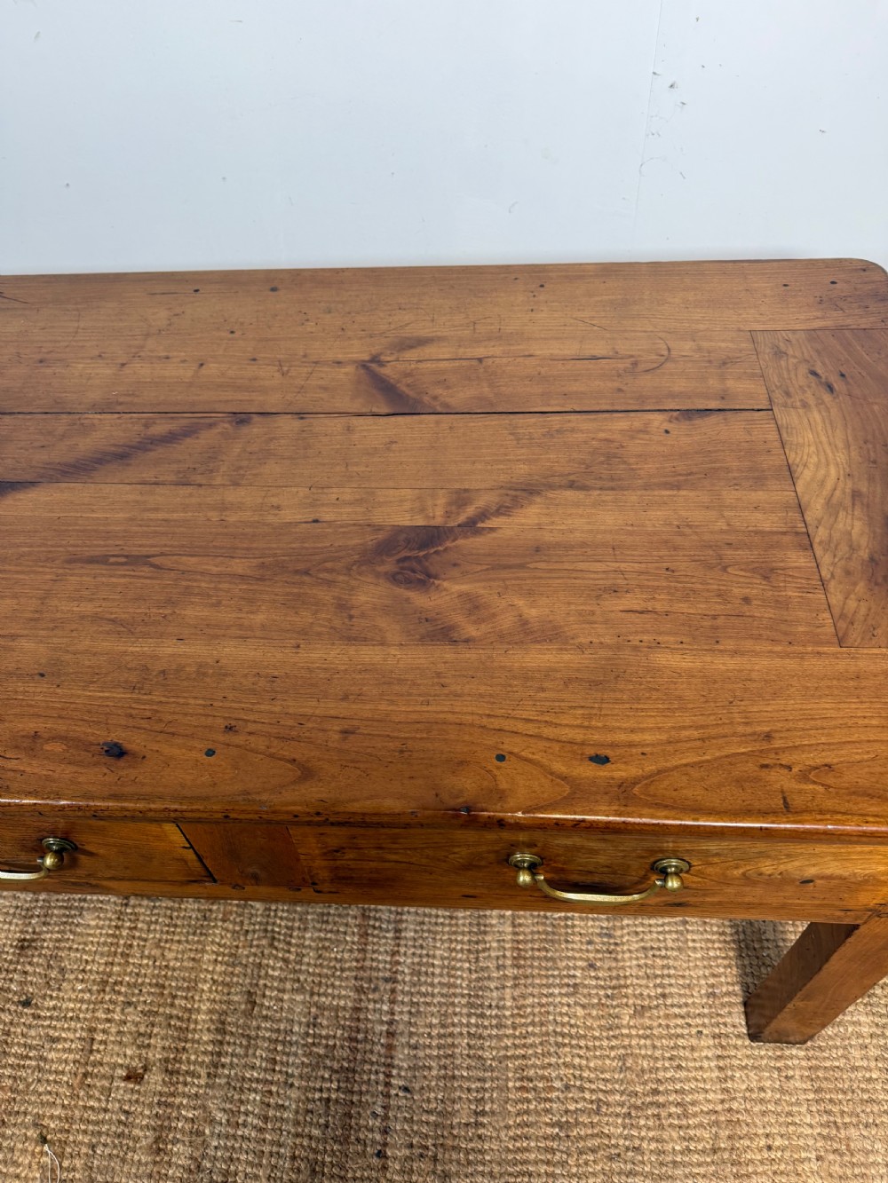 A 19th-century French provincial wooden dresser base featuring three drawers with brass bail handles set on straight legs. View V