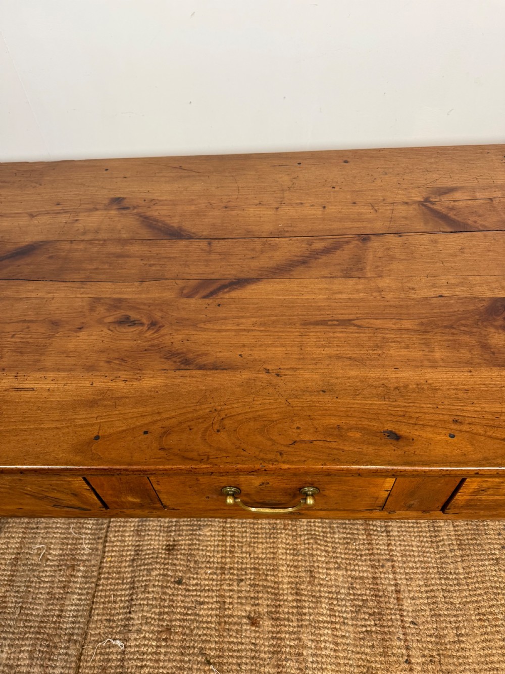 A 19th-century French provincial wooden dresser base featuring three drawers with brass bail handles set on straight legs. View VI