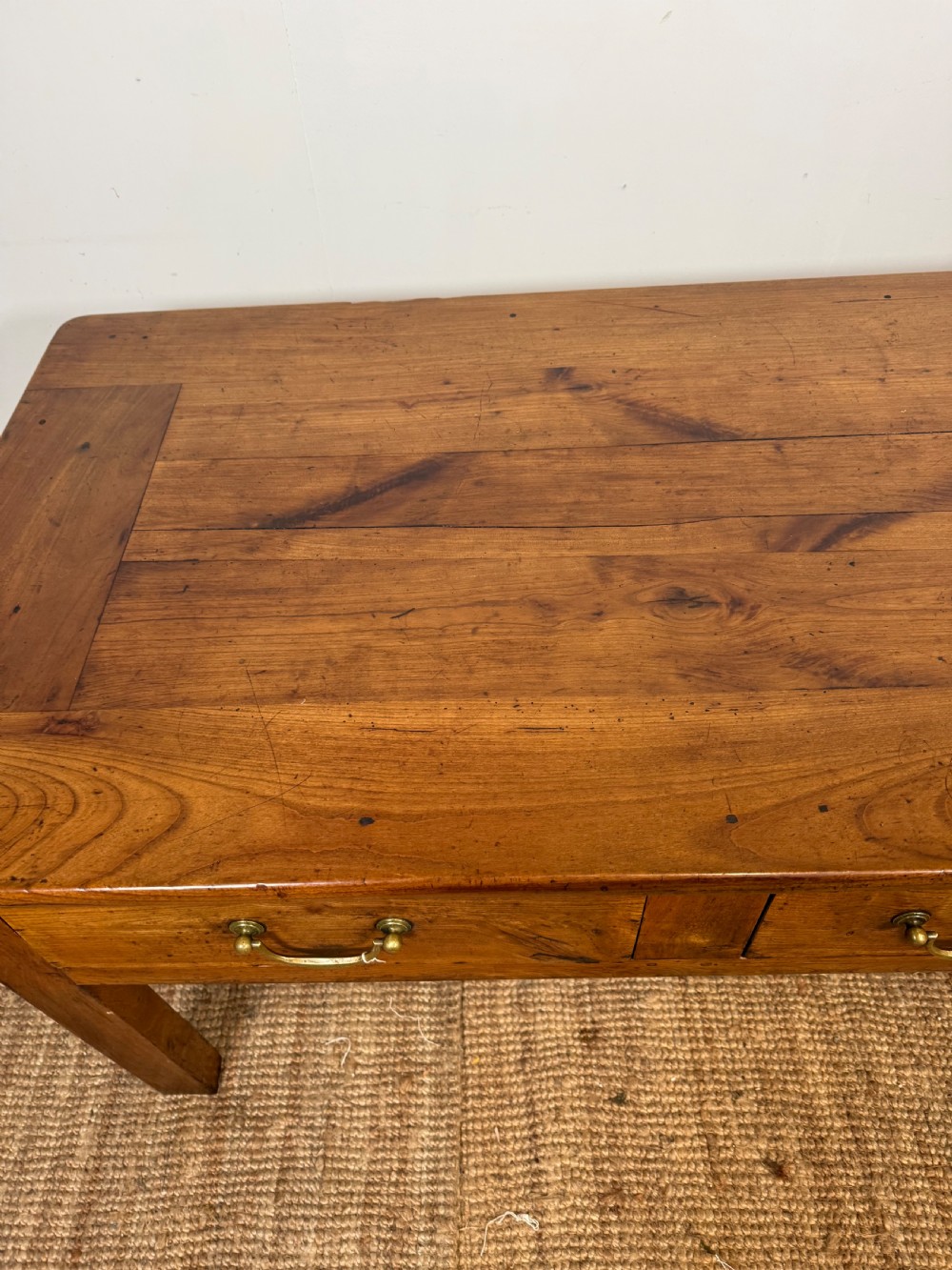 A 19th-century French provincial wooden dresser base featuring three drawers with brass bail handles set on straight legs. View VII
