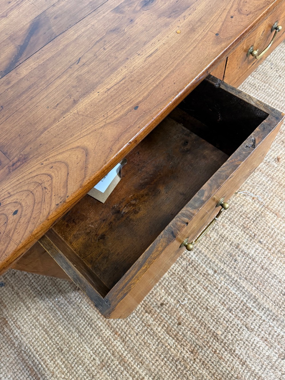 A 19th-century French provincial wooden dresser base featuring three drawers with brass bail handles set on straight legs. View XI