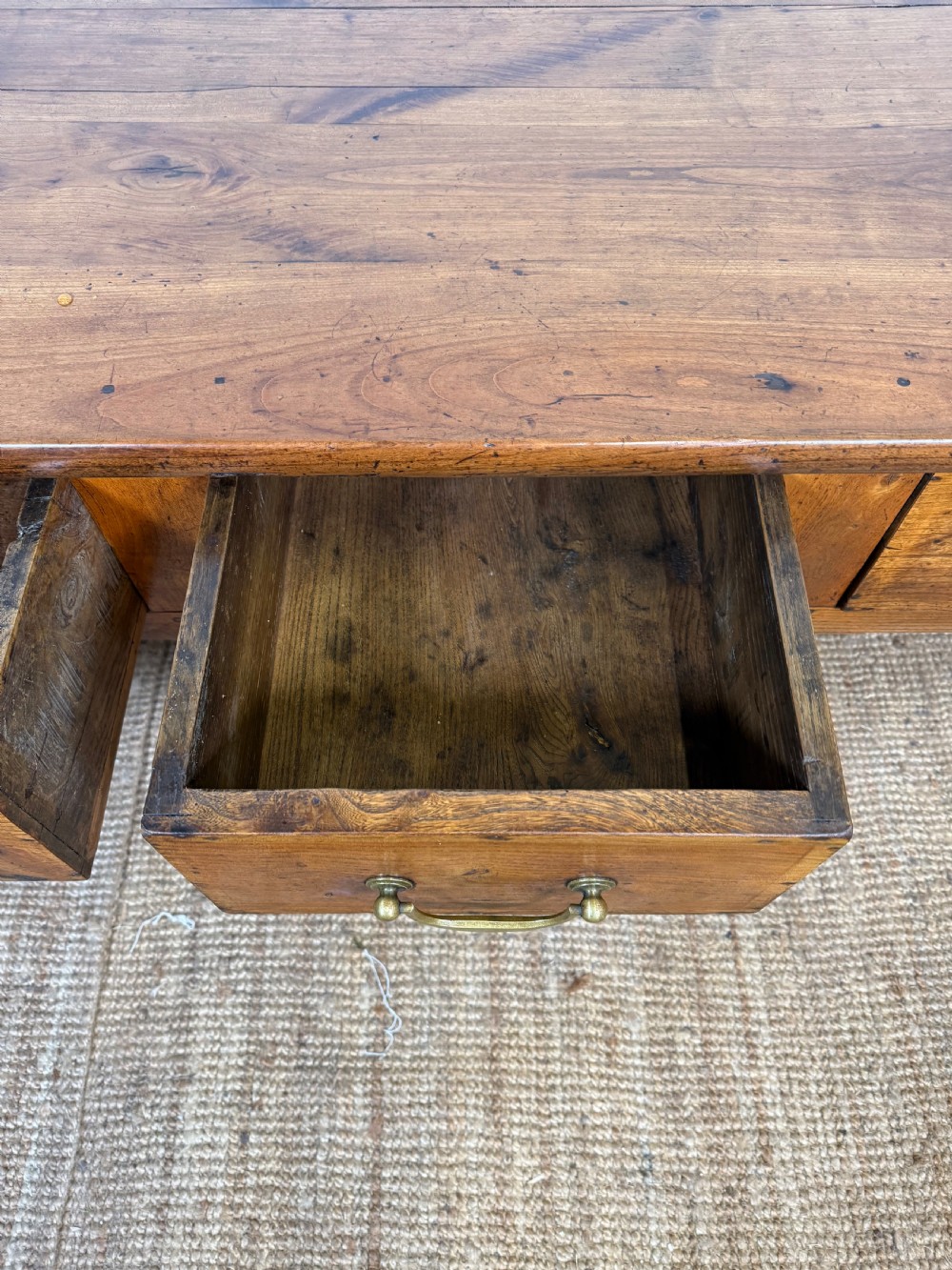 A 19th-century French provincial wooden dresser base featuring three drawers with brass bail handles set on straight legs. View XII