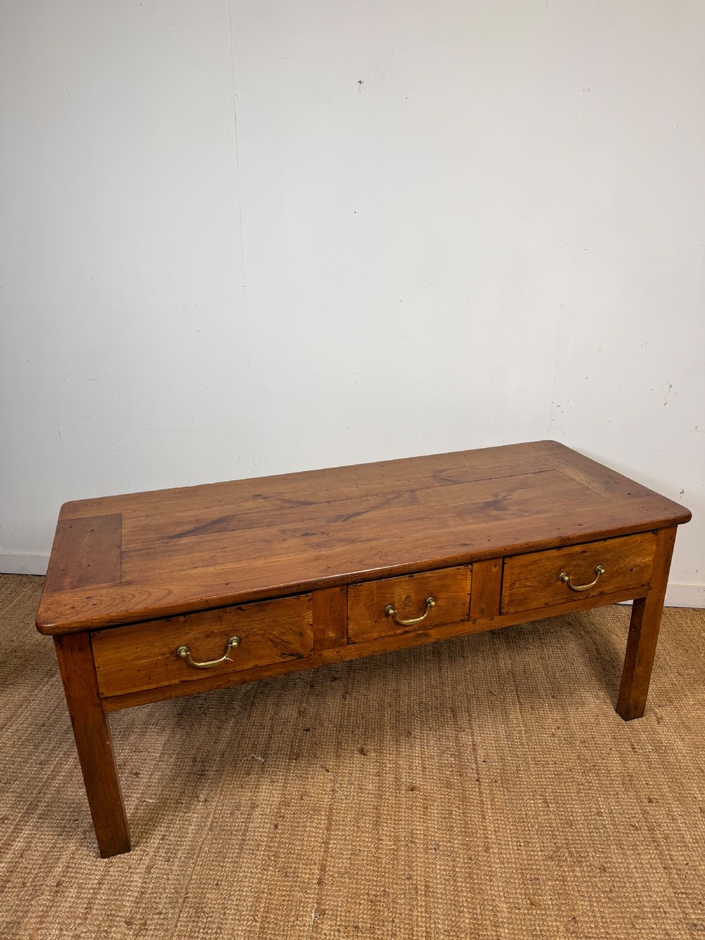 A 19th-century French provincial wooden dresser base featuring three drawers with brass bail handles set on straight legs. View XIII