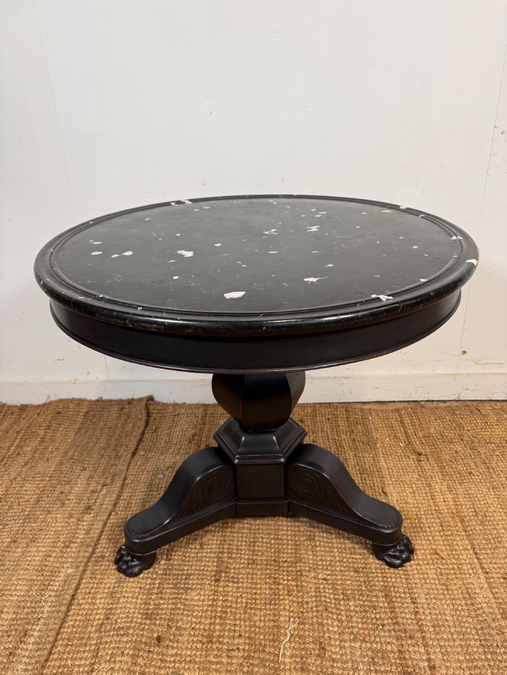A 19th-century French circular gueridon side table featuring a dark speckled marble top, black painted pedestal support, and scroll feet.
