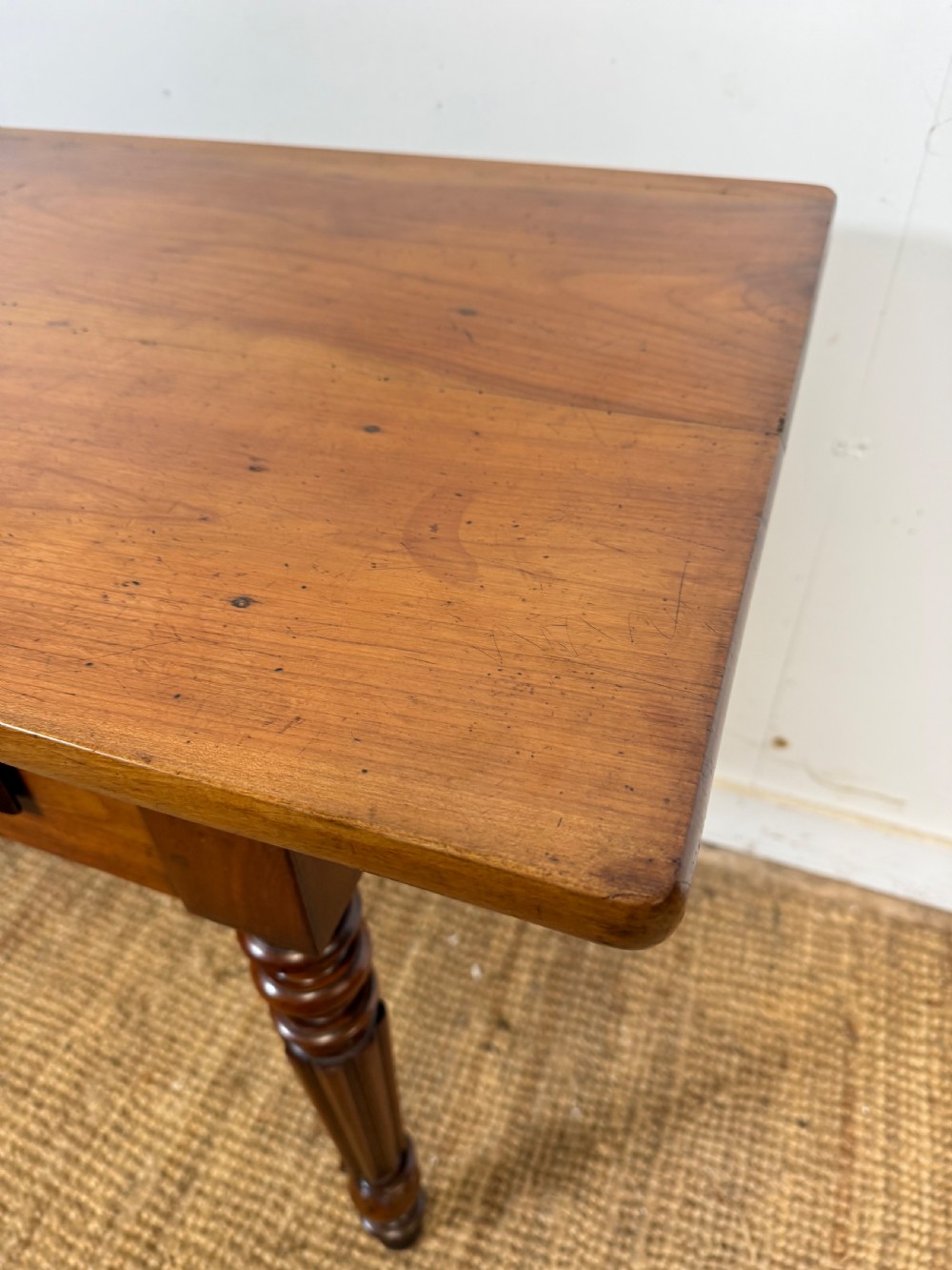 A 19th-century French cherrywood console table featuring two frieze drawers with brass knobs and four turned, fluted legs. View IV