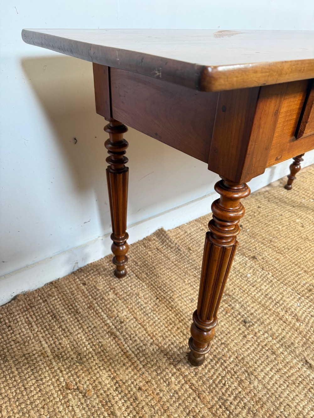 A 19th-century French cherrywood console table featuring two frieze drawers with brass knobs and four turned, fluted legs. View IX