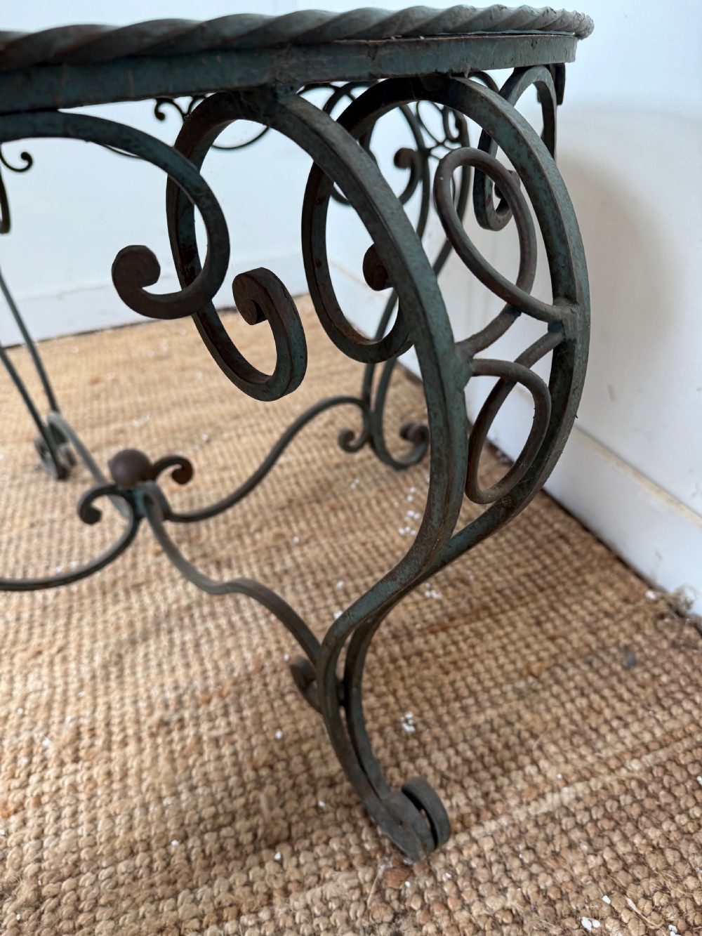 A round Art Deco coffee table featuring a verdigris wrought iron frame with scroll legs and a circular glass top decorated with a painted floral border. View VIII