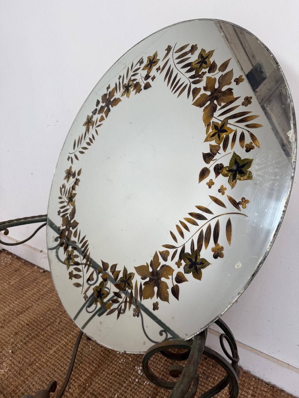 A round Art Deco coffee table featuring a verdigris wrought iron frame with scroll legs and a circular glass top decorated with a painted floral border. View XI
