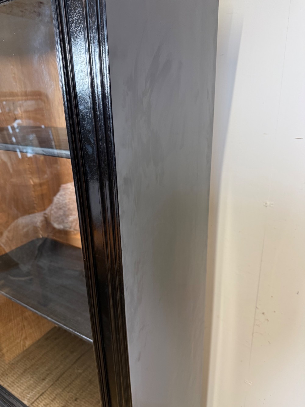 A narrow 19th-century Napoleon III ebonised wooden bookcase featuring a single glazed glass door, decorative gilt brass mounts, and a warm oak lined interior. View III