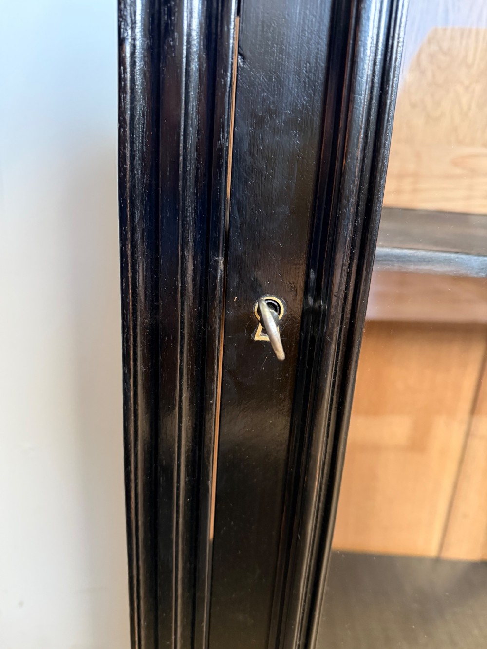 A narrow 19th-century Napoleon III ebonised wooden bookcase featuring a single glazed glass door, decorative gilt brass mounts, and a warm oak lined interior. View VII