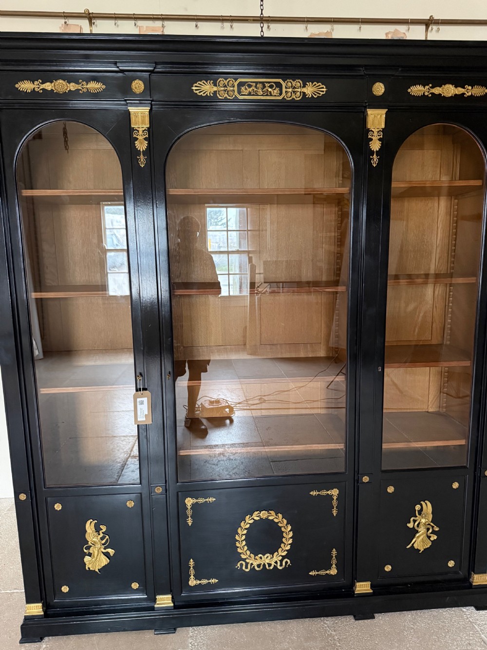 A large ebonised three-door glazed bookcase featuring gold-toned gilt-bronze mounts, arched glass panels, and an oak interior. View III