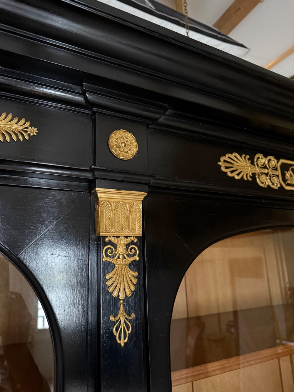A large ebonised three-door glazed bookcase featuring gold-toned gilt-bronze mounts, arched glass panels, and an oak interior. View IV