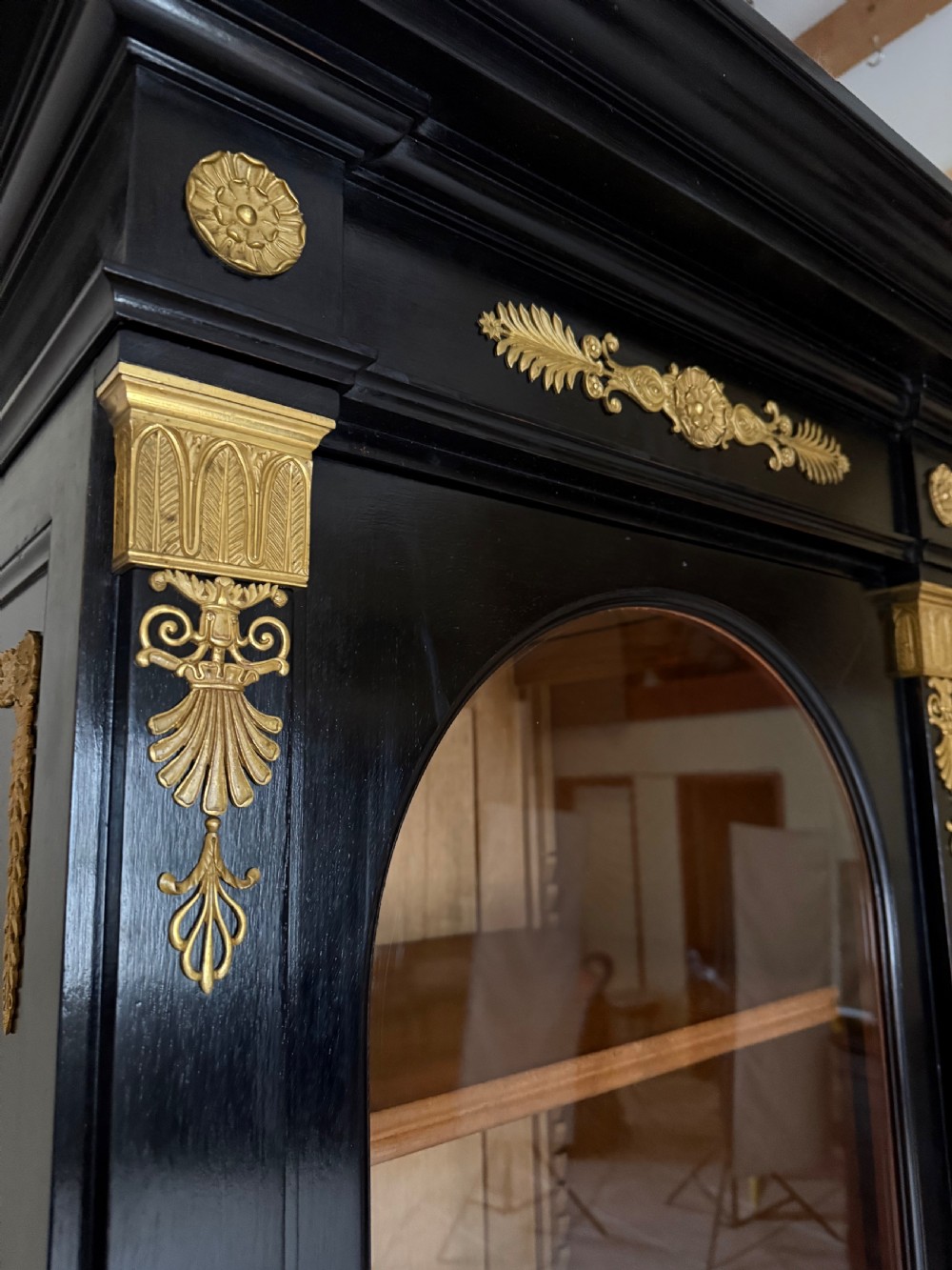 A large ebonised three-door glazed bookcase featuring gold-toned gilt-bronze mounts, arched glass panels, and an oak interior. View V